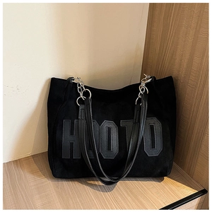 Close-up of the HOOTO letter design on a black plush tote bag with a chain shoulder strap
