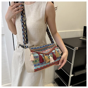 Detailed close-up of ethnic woven shoulder bag with colorful tassels and jacquard strap