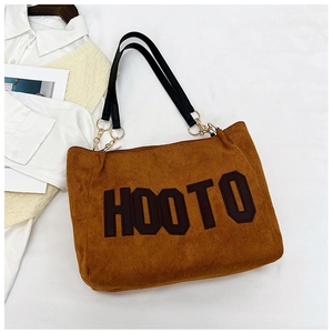 Close-up of brown suede tote bag with bold HOOTO letters and black leather straps