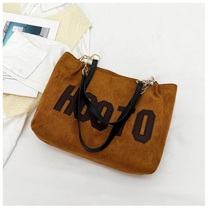 Detail of soft brown suede tote bag featuring large HOOTO letter print and black leather straps