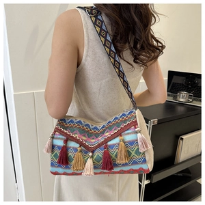 Detail of bohemian knit bag featuring colorful fringe tassels and geometric patterned strap