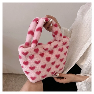 Detailed texture of pink plush tote bag with red heart pattern held by a model