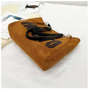 Detail of caramel brown plush tote bag with letter print and gold hardware connectors