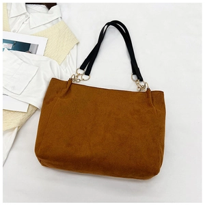Detail view of large brown plush tote bag with black leather straps and gold metal rings