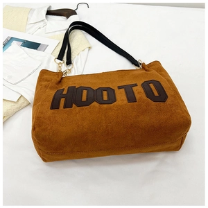 Detail of brown suede tote bag with HOOTO letter patch and black leather strap