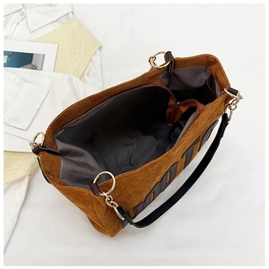 Detail view of large brown plush tote bag interior with zipper pocket and metal buckles