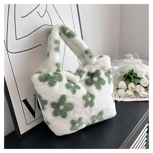 Close-up of soft beige faux fur tote bag with green floral pattern on black surface