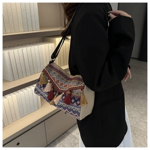 Detail of woven bohemian shoulder bag with colorful tassels and geometric jacquard texture