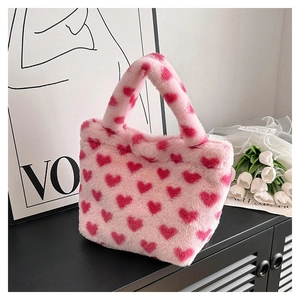 Detail shot of a soft pink plush handbag featuring cute red heart patterns and fluffy texture