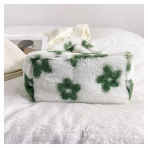 Close-up of fluffy white plush tote bag with green floral pattern in a cozy home setting