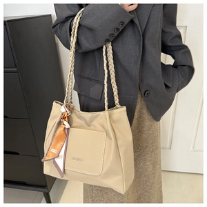 Dettaglio borsa a secchiello beige con manico intrecciato e foulard in seta decorativo