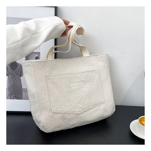 Detail of the white plush tote bag showing the fashion label and soft fuzzy texture