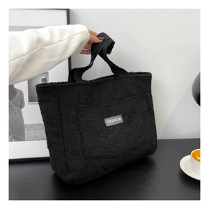 Detail of black plush tote bag featuring soft faux fur texture and Fashion brand label