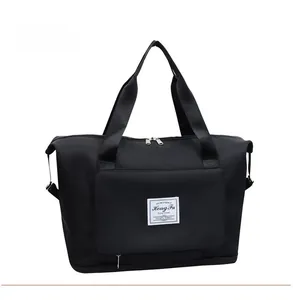 Detail of black large capacity travel bag featuring spacious front pocket and woven handles
