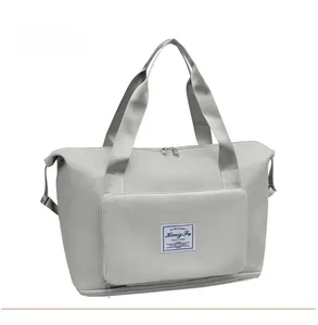 Detail view of large grey travel bag showing reinforced handles and front zip pocket