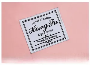 Close-up of a pink fabric travel bag featuring a white stitched logo patch with travel text