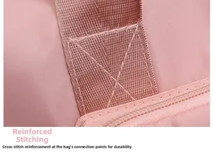 Detailed close-up of reinforced cross-stitching on the pink fabric travel bag handle