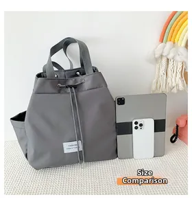 Deep grey drawstring backpack showing internal capacity with tablet and phone comparison