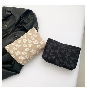 Détail de la texture florale sur les pochettes de rangement souples beige et noir