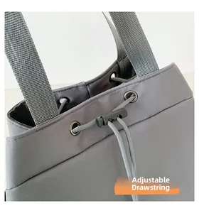 Detailed view of the adjustable drawstring and textured nylon fabric on the gray handbag