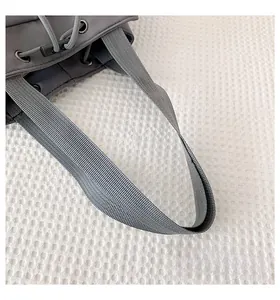 Detailed close-up of grey nylon fabric bag featuring a sturdy strap and drawstring closure
