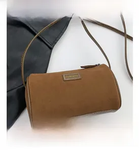 Détail d'un sac bandoulière cylindrique en velours marron avec garniture et sangle en cuir