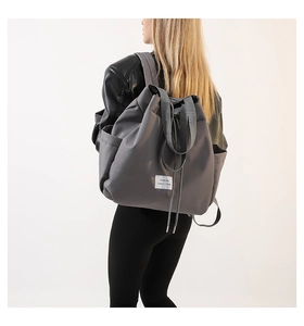 Detail view of the gray nylon drawstring backpack with side pockets and a white square label