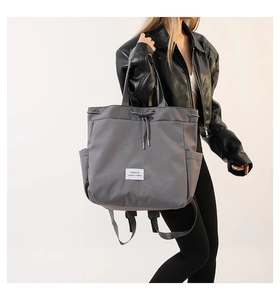 Detail view of the drawstring closure and woven logo on this grey nylon tote bag