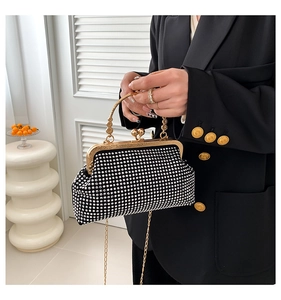 Detail of black rhinestone evening clutch with gold metal handle and chain strap for women