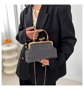Chic black evening bag with silver rhinestones and gold chain handle on a stylish model