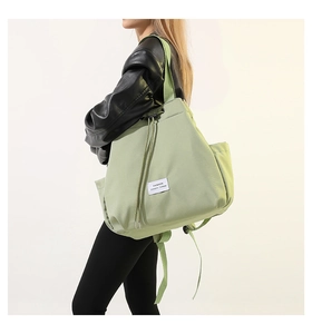 Detail of light green nylon drawstring backpack with white fashion label on surface