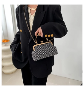 Detail view of a black rhinestone evening clutch with gold handle and vintage clasp