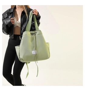 Detail of light green drawstring tote bag featuring nylon fabric texture and fashion label