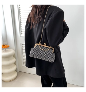 Detail of a sparkling black rhinestone clutch bag with gold round handle and chain
