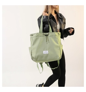 Detail of light green nylon tote bag featuring a drawstring closure and white fashion label