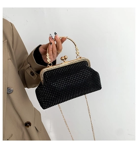 Detail of black rhinestone evening bag with gold floral handle and metal chain strap