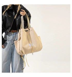 Detail view of beige nylon tote bag with drawstring closure and stylish side pockets