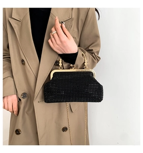 Detailed macro view of black rhinestone clutch bag with gold metallic frame and ball clasp