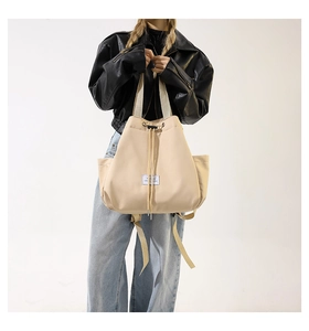 Detailed view of beige nylon multi-way bag showing drawstring closure and brand label