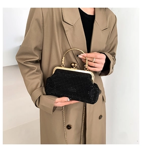 Detail of black rhinestone evening bag with gold ring handle and metallic chain strap