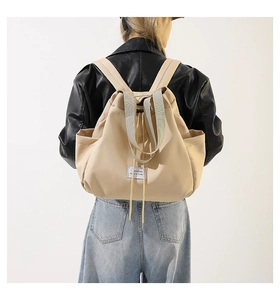 Detail of beige nylon drawstring backpack with side pockets and webbing handle