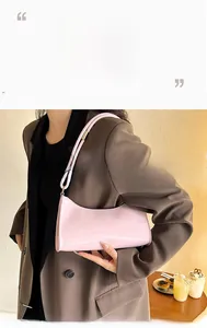 Détail d'un sac baguette en cuir verni rose clair avec boucle métallique sur la bandoulière