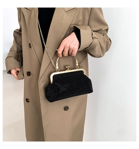 Detail of black rhinestone evening bag with gold chain strap on a khaki trench coat