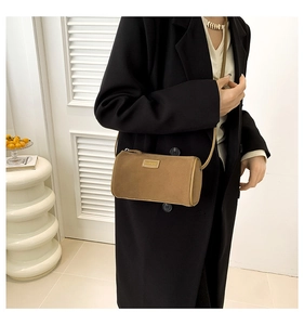 Gros plan du sac cylindrique en velours marron avec logo en métal et fermeture éclair