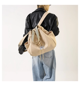 Detail of beige nylon drawstring crossbody bag with side pocket and adjustable strap