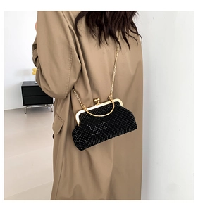 Detail of elegant black rhinestone evening bag with gold chain strap on winter coat