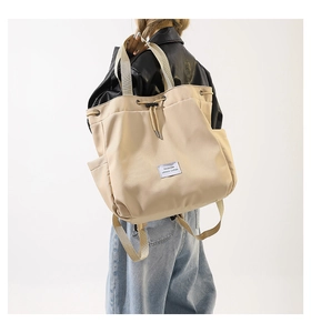 Detail view of beige nylon backpack showing drawstring closure and durable canvas texture