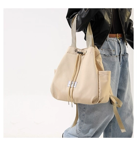 Model showcasing off-white nylon drawstring tote bag with a minimalist square label