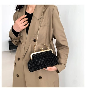 Detail of black rhinestone evening clutch bag with gold ring handle on camel coat