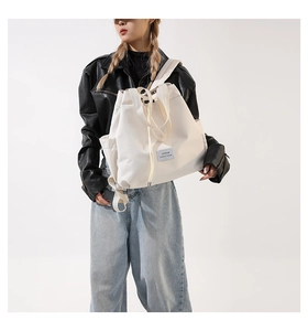 Detail of a beige nylon drawstring bag with a fashion leisure label and side view on model